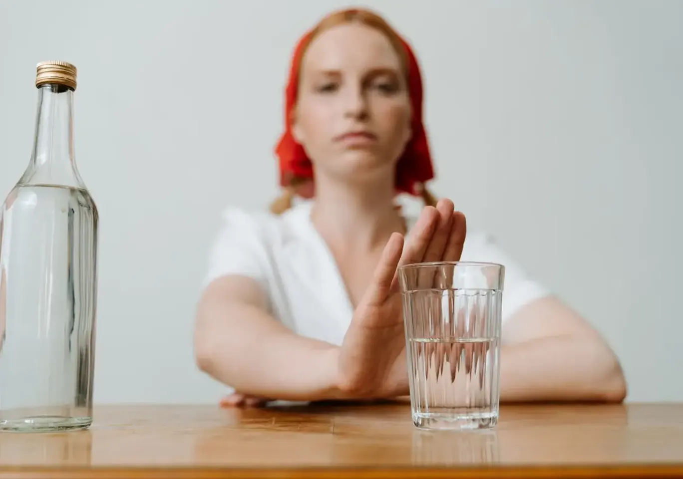 Leczenie alkoholizmu Zamość: kobieta odsuwa butelkę i sięga po wodę